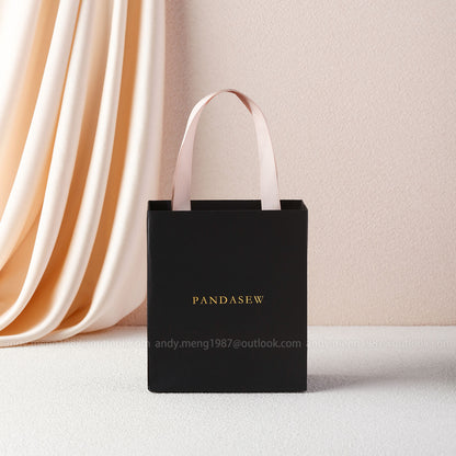 black paper bag with gold debossed logo. The ribbon is also texture cotton ribbon